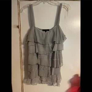 Sleeveless grey blouse with ruffles.